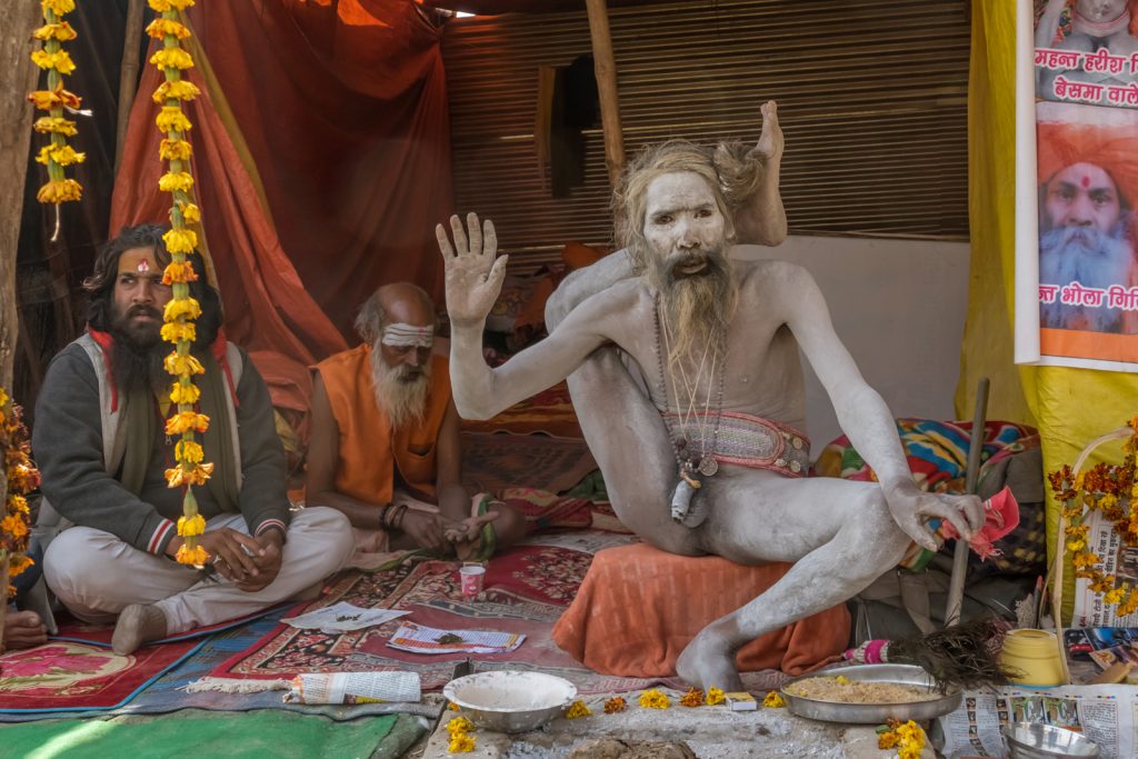 Naga sadhu in a complex yoga pose at Kumbh Mela India - World's Largest Gathering