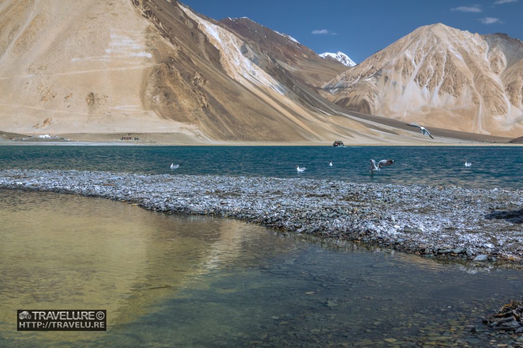 Majestic backdrop of barren mountains help highlight the blue-green hues...