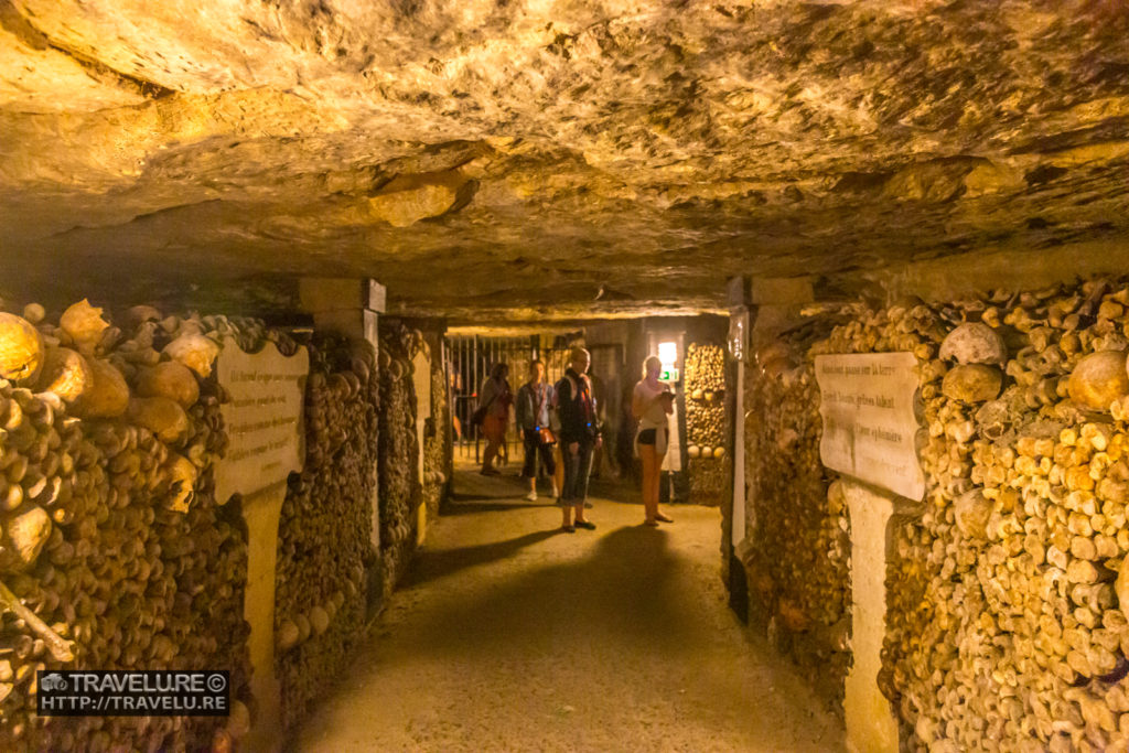 Visitors taking in the strange sight of the oddest filing cabinet in the world - the Catacombs in Paris - Travelure ©