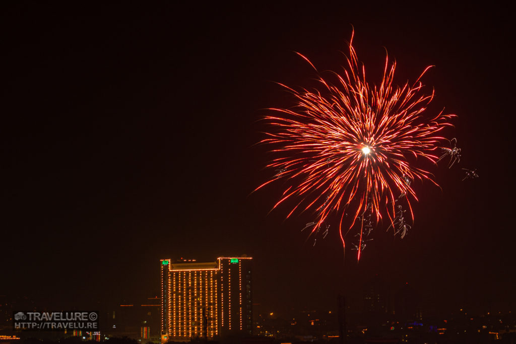 Fireworks in the foreground of a lit-up city building - Simple Steps to Shoot Fireworks - Travelure ©