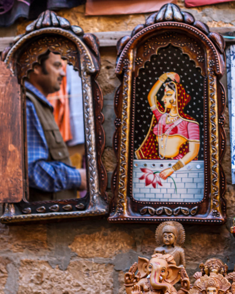 A tourist frames himself in an ethnic mirror being hawked - Travelure ©