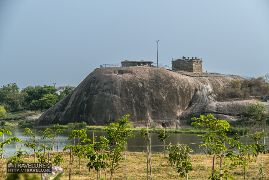 Fort structures built atop the boulders. A waterbody forms the foreground. - Travelure ©